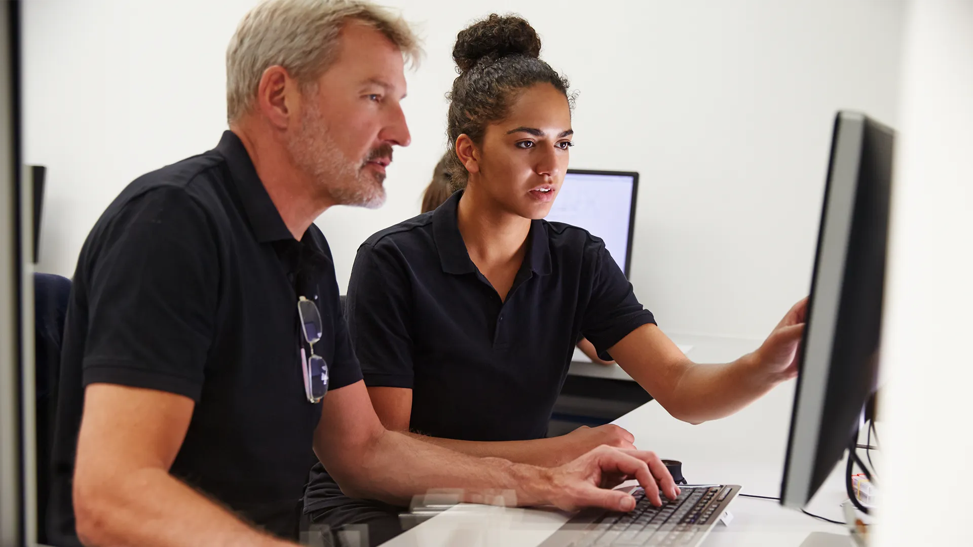 Guy teaching a student on the computer